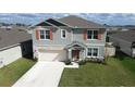 Two-story home with stone accents, two-car garage, well-manicured lawn, and neutral colored facade at 421 Chayne Pl, St Cloud, FL 34771
