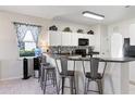 Bright kitchen featuring white cabinets, a breakfast bar with seating, and modern appliances at 14439 Prunningwood Pl, Winter Garden, FL 34787