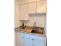 Close-up of the kitchen sink with granite countertops and white cabinetry at 1700 6Th Nw St # A36, Winter Haven, FL 33881