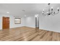 Inviting living room with wood-look floors, a modern chandelier, and a natural light from the window at 2465 Thornhill Rd, Auburndale, FL 33823