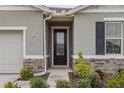 Close-up of the front door with a black frame, decorative glass, and stone veneer accents at 5431 Arlington River Dr, Lakeland, FL 33811