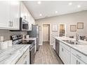 This open kitchen features modern stainless steel appliances, white cabinets and stylish countertops at 722 Bentley North Loop, Auburndale, FL 33823