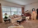 Elegant living room featuring a grand piano, comfortable seating, and natural light at 940 Ashton Oaks Cir, Lakeland, FL 33813