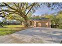 Spacious driveway leading to a tan single-story home with an attached two-car garage at 1 Lake Eloise Ln, Winter Haven, FL 33884