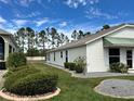 This home has a manicured lawn and mature landscaping, with a partial view of the home's exterior at 1155 Motorcoach Dr, Polk City, FL 33868