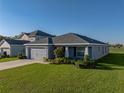 View of a single-story home with a gray exterior, well-manicured lawn and landscaping, and a two-car garage at 236 Talladega Ln, Polk City, FL 33868