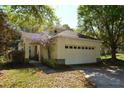 Neutral colored home featuring mature landscaping and a two car garage at 6620 Lake Clark Dr, Lakeland, FL 33813