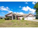 Charming single-story home featuring a two-car garage, well-manicured lawn, and delightful landscaping at 107 Amber Blvd, Auburndale, FL 33823