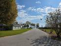 Street view leading to waterfront homes with lush green lawns and a serene blue sky at 107 Amber Blvd, Auburndale, FL 33823