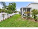 Fenced backyard with lush lawn, mature landscaping, and a screened lanai at 117 Belmont Dr, Winter Haven, FL 33884