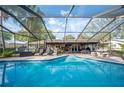 Inviting screened-in pool with clear blue water, surrounded by patio furniture, palm trees, and lush landscaping at 1311 Glengreen Ln, Lakeland, FL 33813