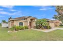 Charming single Gathering home featuring lush landscaping, stone accents, mature palms, and a two car garage at 2030 Country Manor St, Bartow, FL 33830