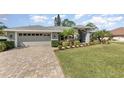 Charming single-story home featuring a manicured lawn, palm trees, and a neatly landscaped garden at 3001 Plantation Rd, Winter Haven, FL 33884