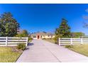 A sprawling yellow home with a red door, set back from the road with a long driveway and white fence at 3533 Britt Rd, Mount Dora, FL 32757