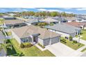 Aerial view of the gray single-story home featuring a well-manicured lawn, landscaping, and a three car garage at 6185 Gracie Pl, Lakeland, FL 33812