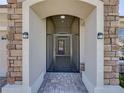 Covered front entry shows stone accents and tiled floor leading to the main door with security door at 8160 Lake James Dr, Lakeland, FL 33810