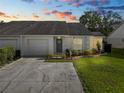 Charming home with a lovely landscaped yard, including an attached garage, captured at sunset at 1021 Meadowood Pointe Rd, Lakeland, FL 33811