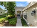 Charming home entrance featuring lush landscaping, a bench, and a decorative exterior light fixture at 1134 Waterfall Ln # 66, Lakeland, FL 33803