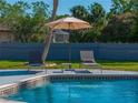 Close-up shot of a pool with an umbrella and two lounge chairs next to it at 121 Greenfield Rd, Winter Haven, FL 33884