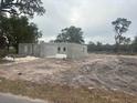 Early construction phase of a block home surrounded by bare land and scattered trees at 3611 E Gaskin Rd, Bartow, FL 33830