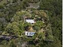 Aerial view of a property with a white boundary showing the house and garage set in a densely wooded area at 4410 Rushing Rd, Lakeland, FL 33810