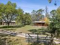 The exterior shows a cozy home and a large garage set against a bright blue sky with plenty of open lawn at 4410 Rushing Rd, Lakeland, FL 33810