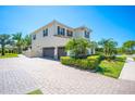 Spacious home with a paver driveway and three-car garage, complemented by mature landscaping and a serene water view at 6515 Eagle View Loop, Lakeland, FL 33813