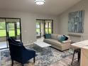 Bright living room featuring a comfortable sofa, stylish blue chairs, and sliding glass doors to the outside at 692 Augusta Rd, Winter Haven, FL 33884