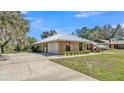 A tan home with a metal roof, stone accents, and a spacious driveway leading to an attached garage at 8621 Plantation Ridge Blvd, Lakeland, FL 33809