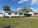 Charming single-story home with well-maintained lawn, carport and mature trees under a blue sky at 129 Nw 10Th Dr, Mulberry, FL 33860