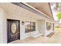 Inviting front porch with a swing, stylish black door, and painted brick facade at 135 Kenilwood Ln, Lakeland, FL 33809