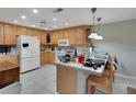 Bright kitchen with wooden cabinets, white appliances, tile countertops, and a casual breakfast bar at 14 Casarena Ct, Winter Haven, FL 33881