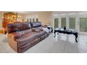 Comfortable living room with a brown leather sofa, white tiled floors, and sliding glass doors to the outside at 14 Casarena Ct, Winter Haven, FL 33881