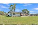 Rear view of a white home with large lawn and a wooden fence with a swing set visible in the distance at 1535 Walker Rd, Lakeland, FL 33810