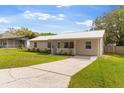 Quaint one-story house featuring a metal roof, a driveway, and green front yard at 227 Dorothy St, Auburndale, FL 33823