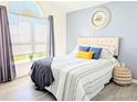 Bright bedroom features a large window, wood-look floors, and a comfortable queen-sized bed at 300 Keswick Ave, Davenport, FL 33897