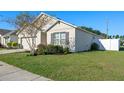 Side of single-story home with a two-car garage, manicured landscaping, and green grass at 301 St Georges Cir, Eagle Lake, FL 33839