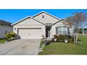Charming single-story home with a two-car garage, stone-lined walkway, and manicured landscaping at 301 St Georges Cir, Eagle Lake, FL 33839