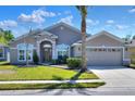 Inviting single-story home featuring a well-manicured lawn, arched windows, and a two-car garage at 4488 Whistlewood Cir, Lakeland, FL 33811