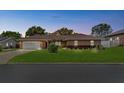 Charming single-story brick home at twilight featuring an attached two-car garage and manicured front lawn at 5432 Weber Pl, Lakeland, FL 33809