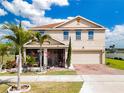 Inviting two-story home featuring a manicured lawn, vibrant tropical landscaping, and a convenient two-car garage at 661 Black Eagle Dr, Groveland, FL 34736