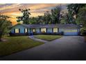 Exterior twilight view of a home, windows illuminated, showing the landscaped yard, and attached garage at 1655 John Arthur Way, Lakeland, FL 33803