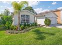 Beautifully landscaped front yard with lush green grass, a palm tree and colorful flowers at 307 Balmoral Ct, Davenport, FL 33896