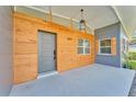 Inviting front porch with modern wood paneling, stylish light fixture and gray accents at 3134 Hilltop S Ave, Lakeland, FL 33803