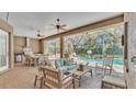 Covered patio featuring outdoor kitchen, ceiling fans, comfortable seating, and pool view at 6774 Crescent Woods Cir, Lakeland, FL 33813