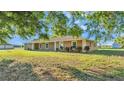 Single-story home with stucco exterior, complemented by green lawn and mature trees with a detached shed in the background at 6981 Snell Rd, Bartow, FL 33830
