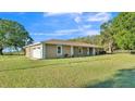A tan home featuring an attached garage, lush lawn, and a well-maintained exterior at 6981 Snell Rd, Bartow, FL 33830