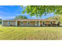Single-story home with beige stucco, crisp white trim, complemented by a lush green lawn and manicured landscaping at 6981 Snell Rd, Bartow, FL 33830