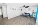 Spacious living room with gray wood-look tile flooring, a ceiling fan, and lots of natural light at 7324 Thomas Jefferson E Cir, Bartow, FL 33830