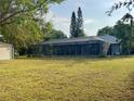 Expansive backyard featuring a large screened-in pool enclosure, lush green grass, and mature trees at 871 Thornburg Rd, Babson Park, FL 33827